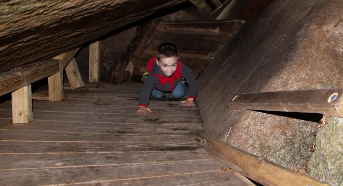 A preschool boy bear crawls through a dark cave.