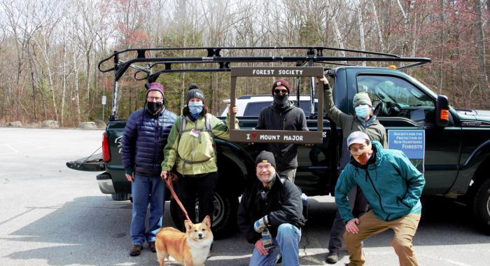 Forest Society staff and volunteers pose in the parking lot at Mt Major with a truck full of collected trash behind them.