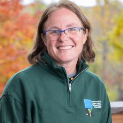 Carrie Deegan poses outside on the deck of the Conservation Center in autumn.