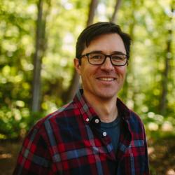 Steve Junkin poses in the forest outside of the Conservation Center.