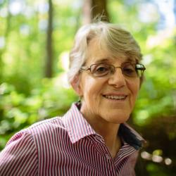 Susanne Kibler-Hacker poses in the forest outside of the Conservation Center.