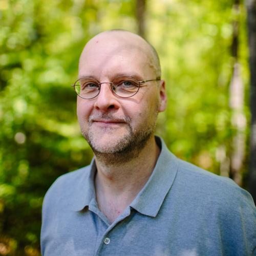 Allan Krygeris poses in the forest outside of the Conservation Center.