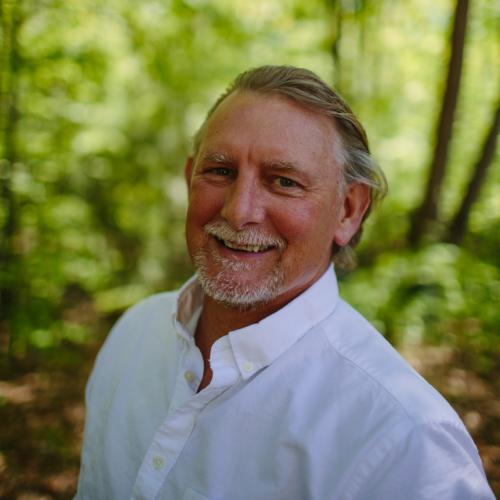 Dave Anderson smiles with the forest in the background.