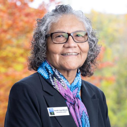 Harriette Yazzie-Whitcomb poses outside on the deck of the Conservation Center in autumn.