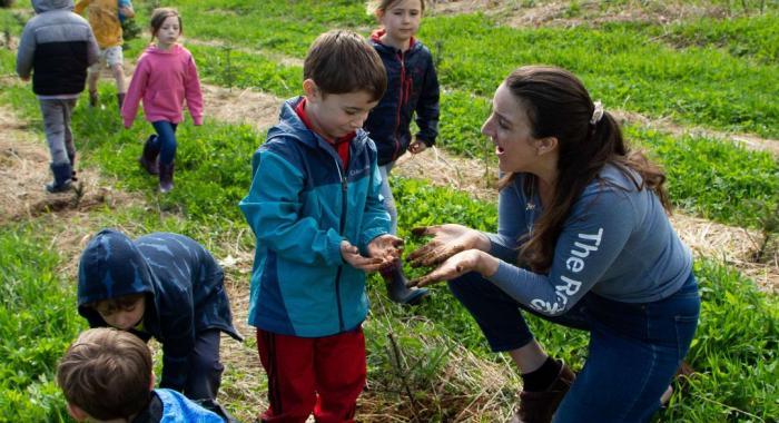 Scarlett Moberly helps a child plant a Christmas tree seedling.