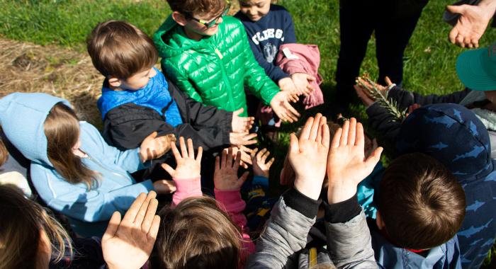 A group of children hold their dirty hands up towards the camera 