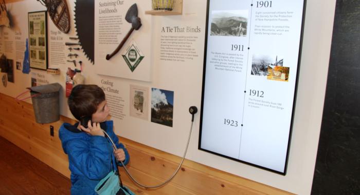 A child listens to audio from an exhibit in the Carriage Barn.