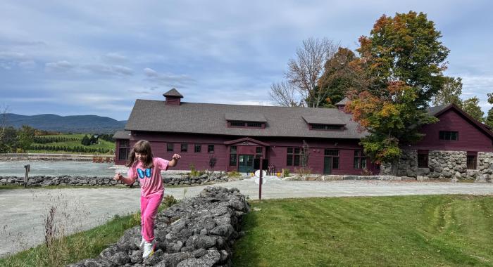 A child walks on the Rock wall in front of the Carriage Barn.