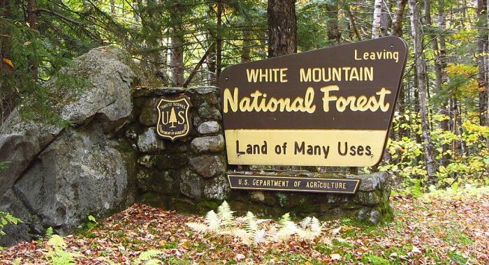 A sign says leaving White Mountain National Forest, land of many uses.