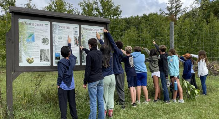 Students point to the sign at Tom Rush Forest.