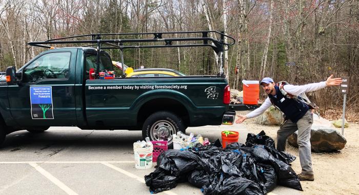 green pick up truck with a number of large trash bags of collected debris.