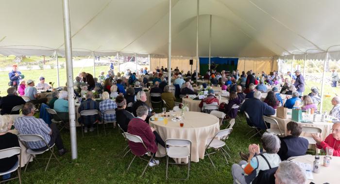 Attendees watch the meeting from under the tent.