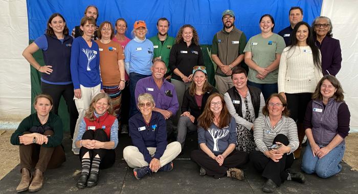 Staff members pose after the Annual Meeting in front of the Forest Society's blue and green flag.