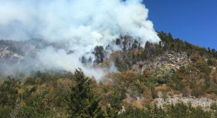 Smoke from a wildfire billowing from a cliff.