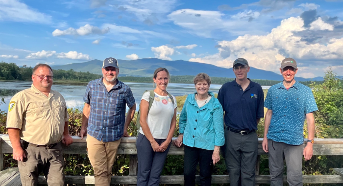 Sen Shaheen and the conservation staff pose in front of Cherry Pond in Whitefield.