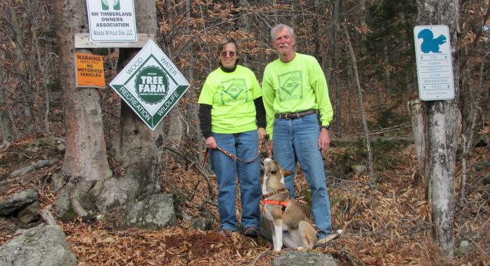 Ann and March Davis pose in front of their Tree Farm with their dog.