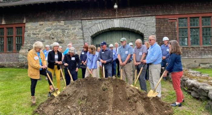 The group poses with golden shovels in front of a pile of dirt.