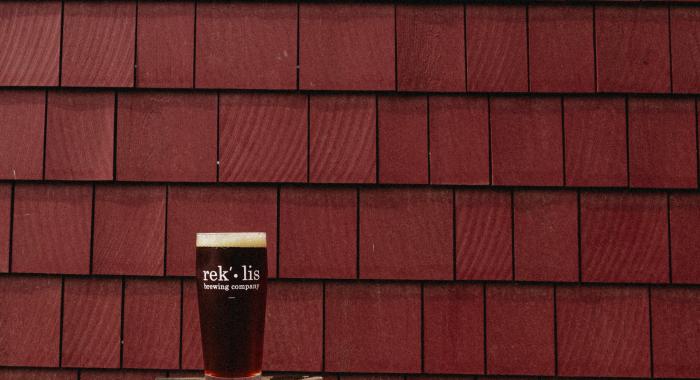 A pint of Rocks Red Ale sits on a stool in front of the renovated barn.