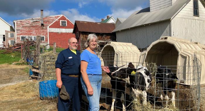 The Morrills stand next to a cow in front of a red barn.