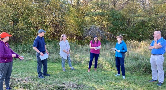 Senator Shaheen stands in the middle of a circle of conservation leaders outdoors at Mink Brook Forest.