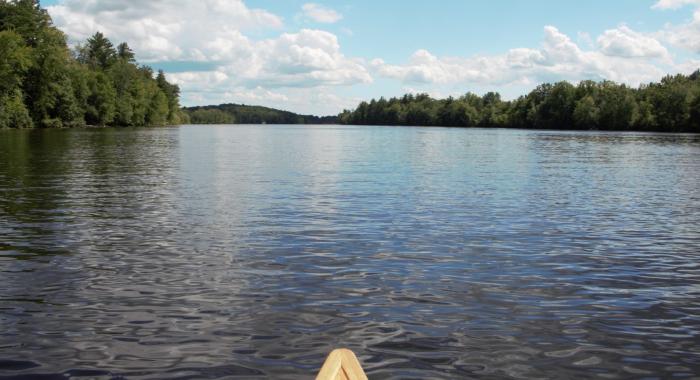 The bow of a canoe with the Merrimack River ahead.