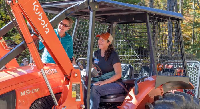 Forest Society Manager Forester Wendy Weisiger helps teach a participant who is driving a tractor.