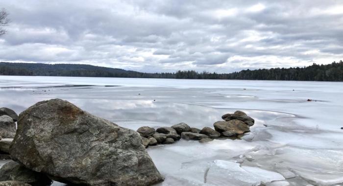 A line of rocks stretches into a frozen winter lake