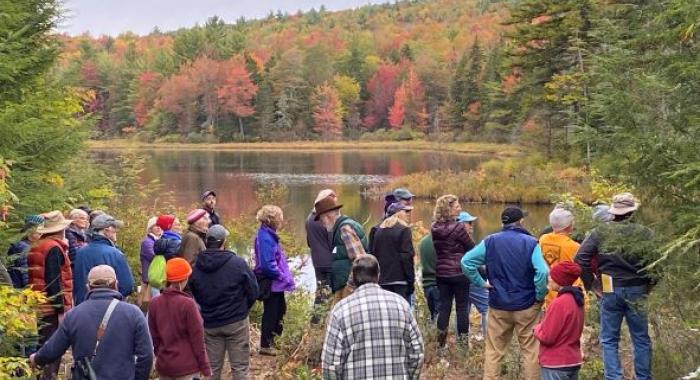colorful hikers, fall foliage along shore of Morrill Marsh pond, Wilmot
