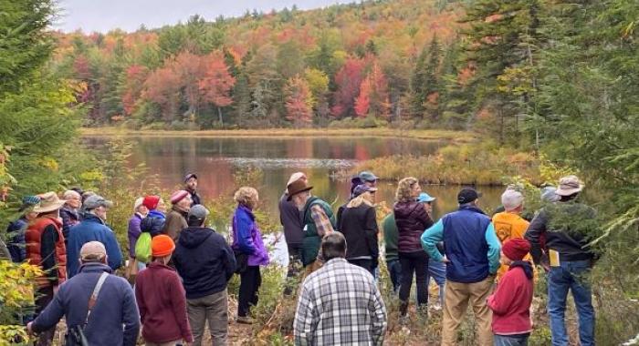 colorful hikers, fall foliage along shore of Morrill Marsh pond, Wilmot