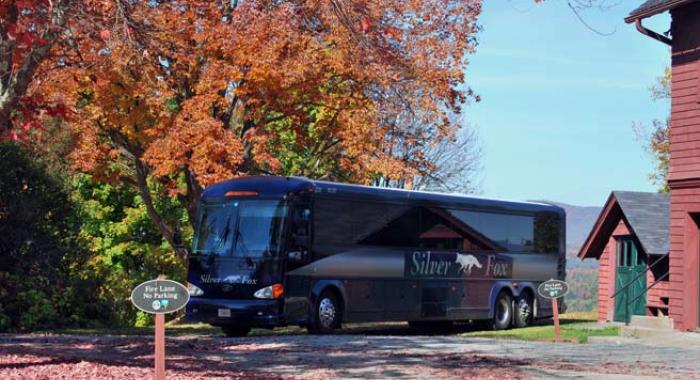 A motorcoach is parked in front of the barn at The Rocks in fall.