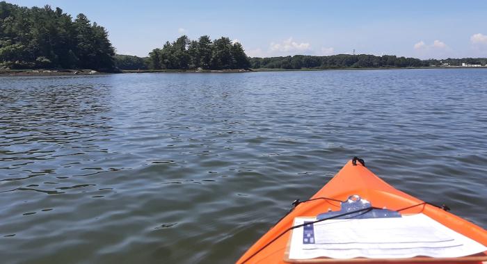 Paddler's view of an orange kayak with clipboard in the ocean