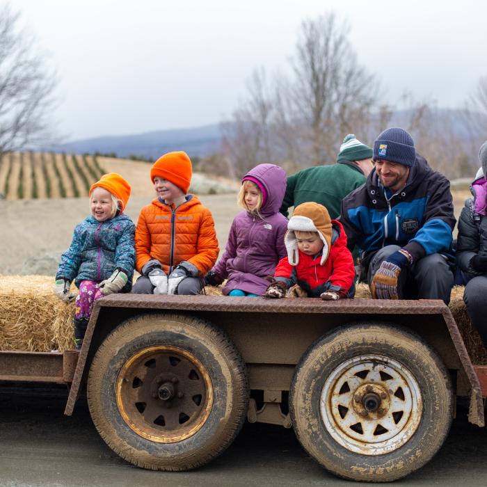 Visitors sit on hay bales during a tractor ride to the Maple Museum.