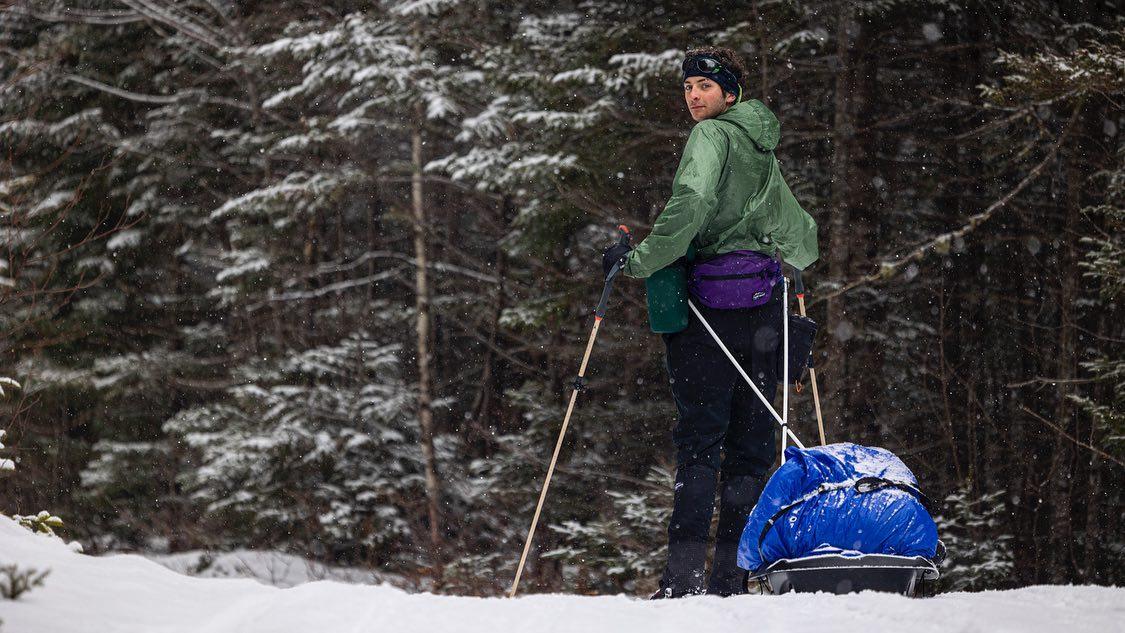 Young man pulls small sled on cross country skis