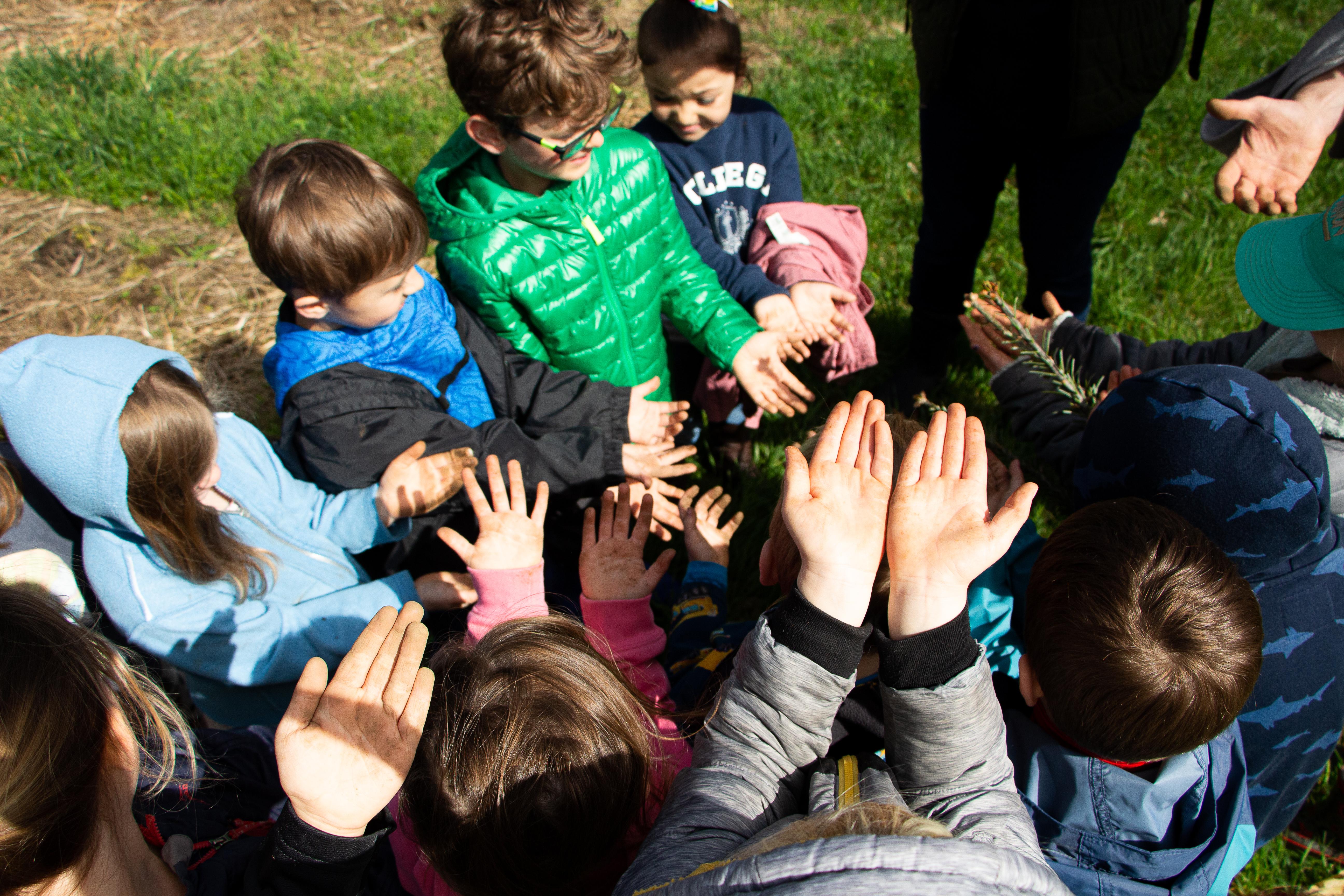 A group of children hold their dirty hands up towards the camera