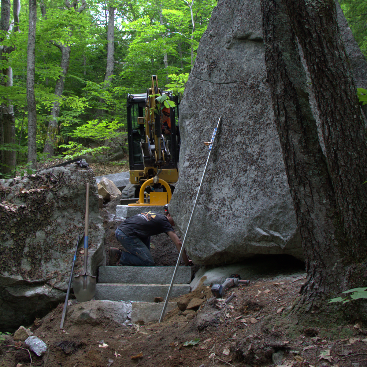 Workers from Town 4 Trails Services build granite steps through a steep section of the trail.