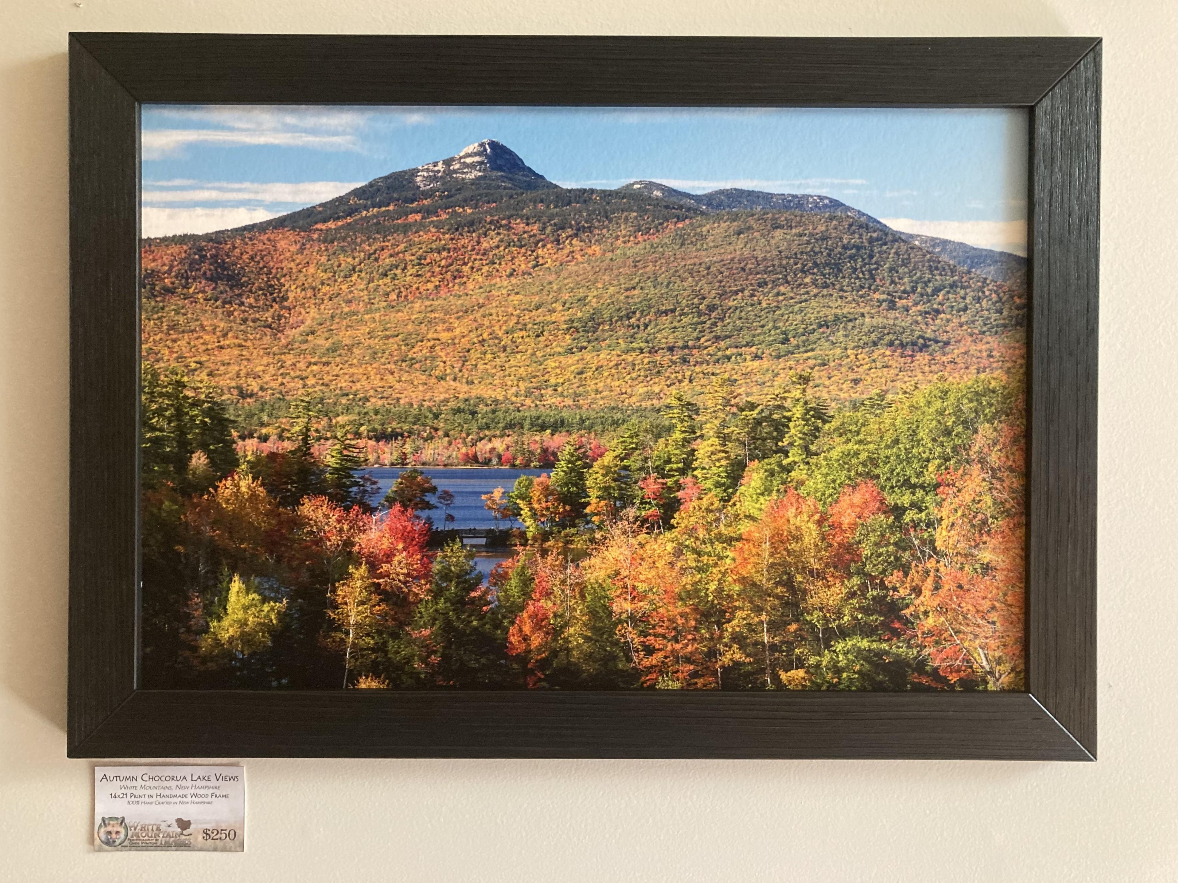 a framed photograph of a lake and mountain during autumn