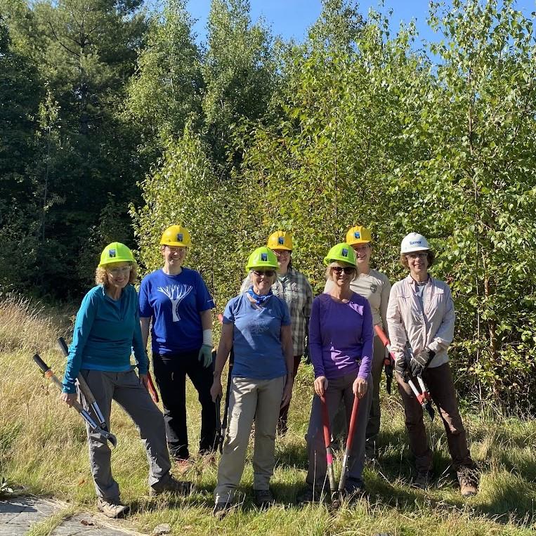 Volunteers pose with tools after clearing brush.