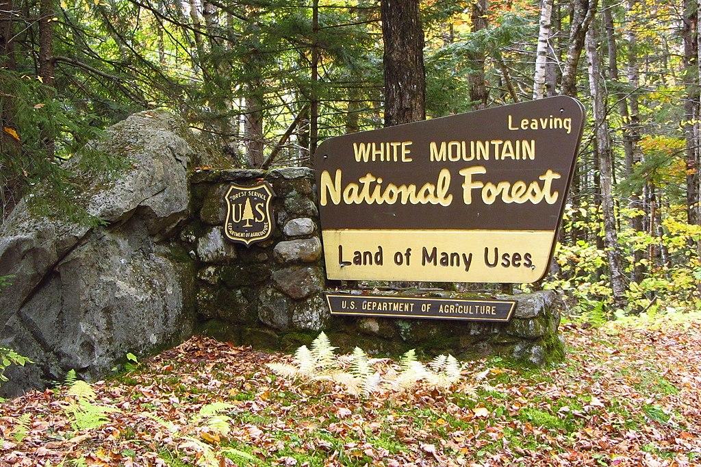 A sign says leaving White Mountain National Forest, land of many uses.