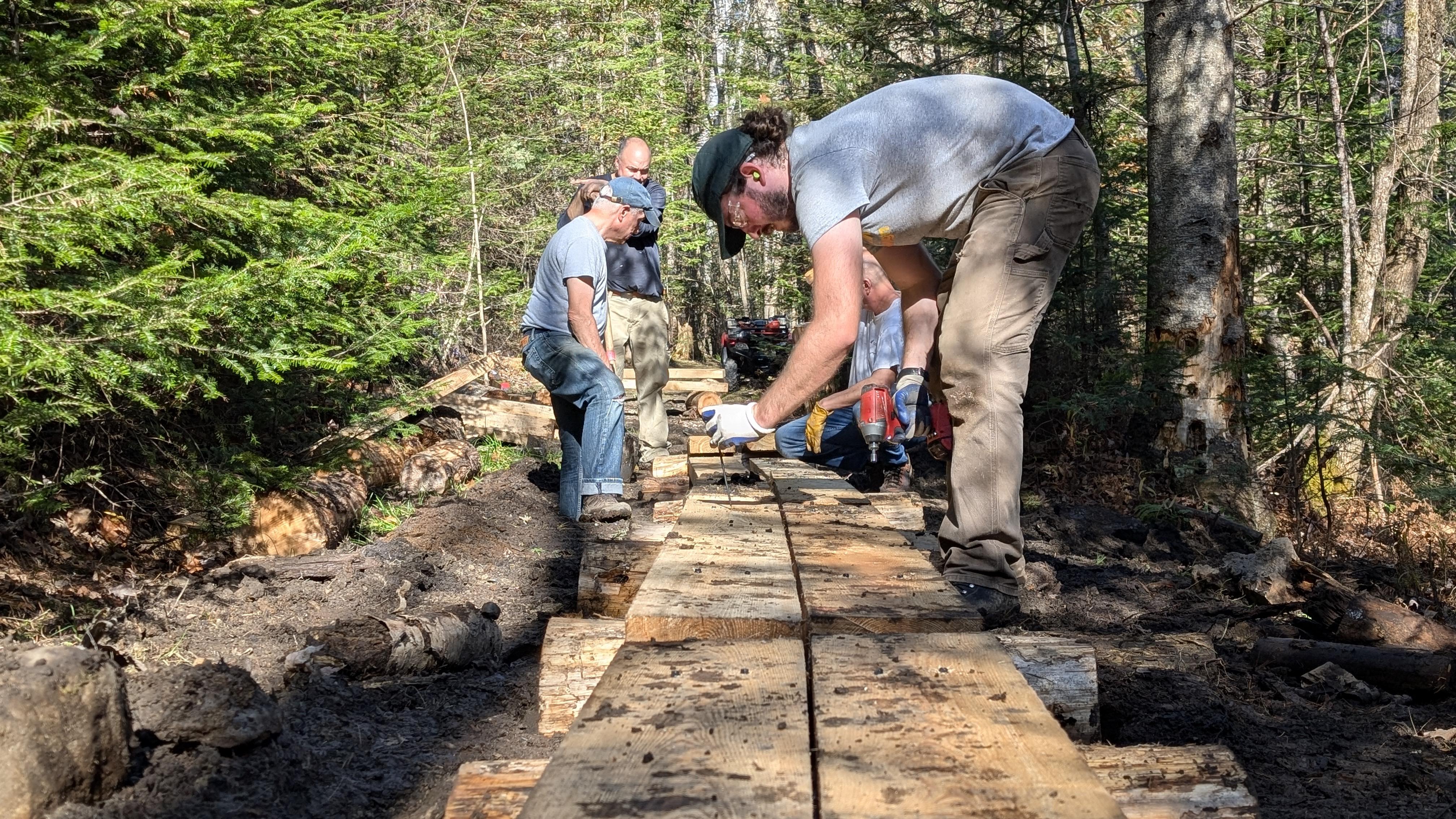 Man in grey t shirt works on wooden bridge