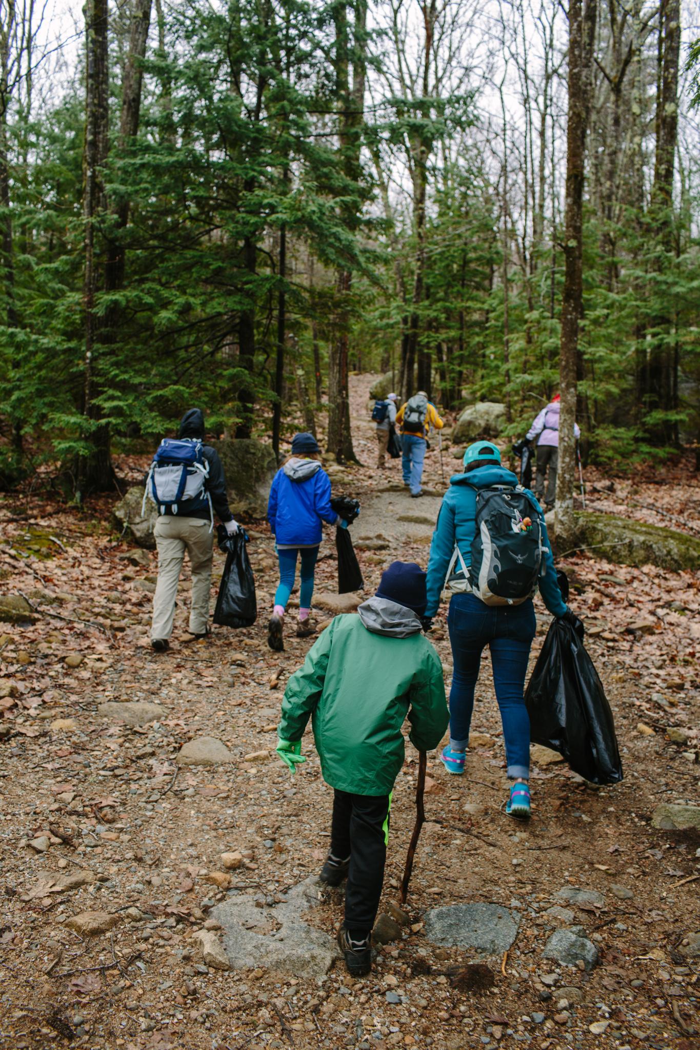 group of hikers walking uphill with packs, sticks and bags