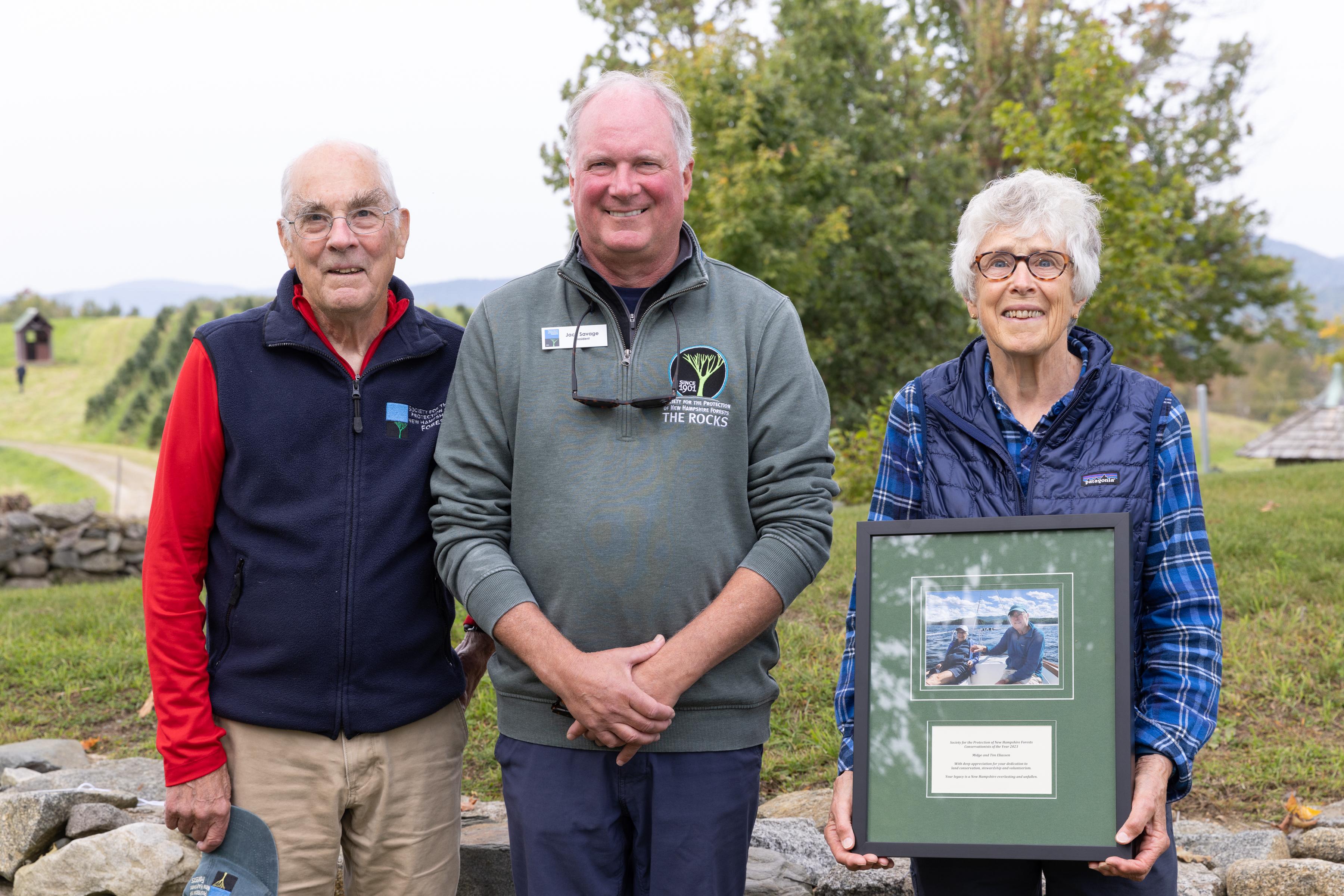 Tim and Midge Eliassen pose with their award with Christmas tree fields in the background.