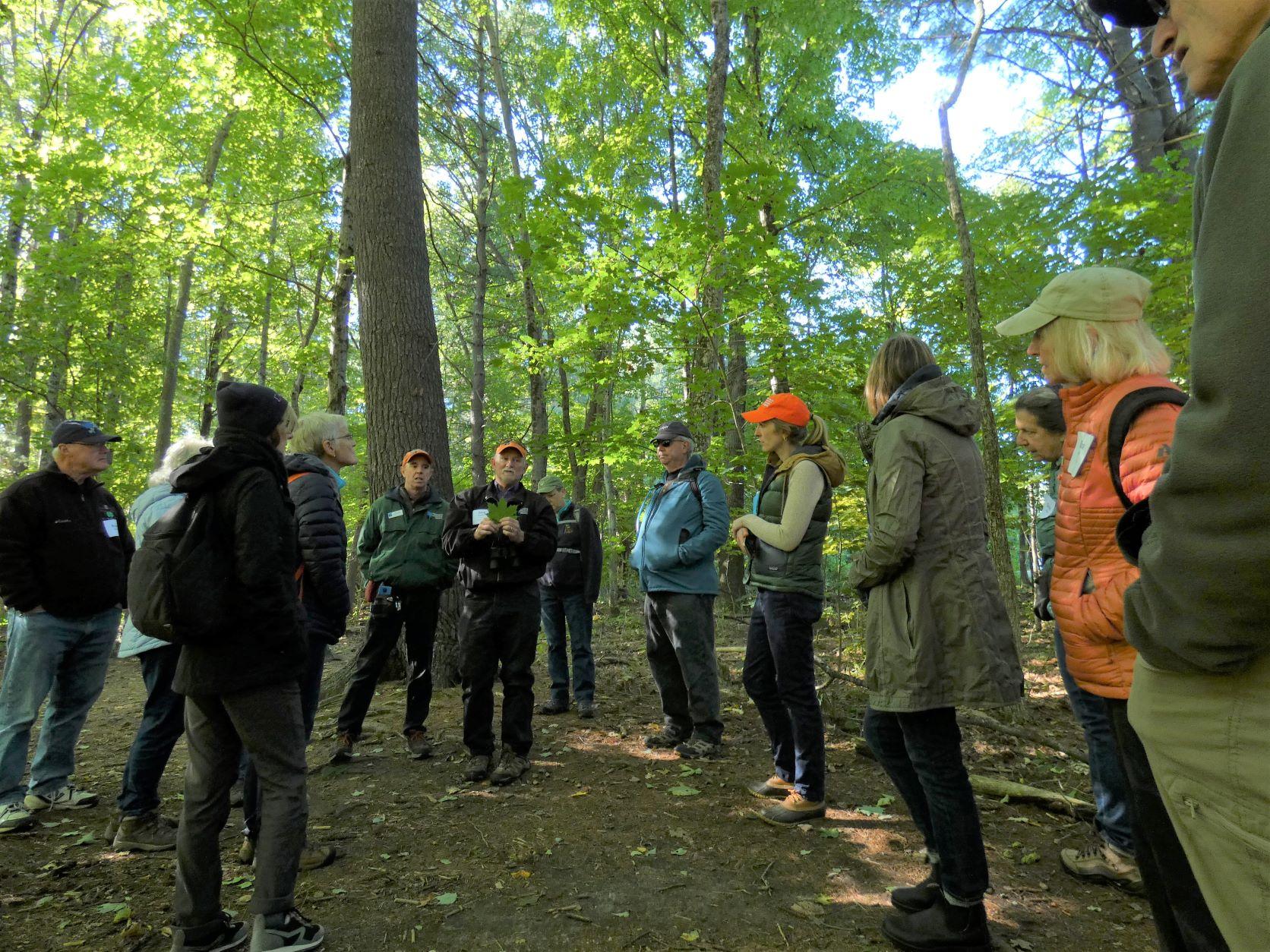 Dave Anderson holds a leaf while talking to attendees during a field trip on the floodplain.