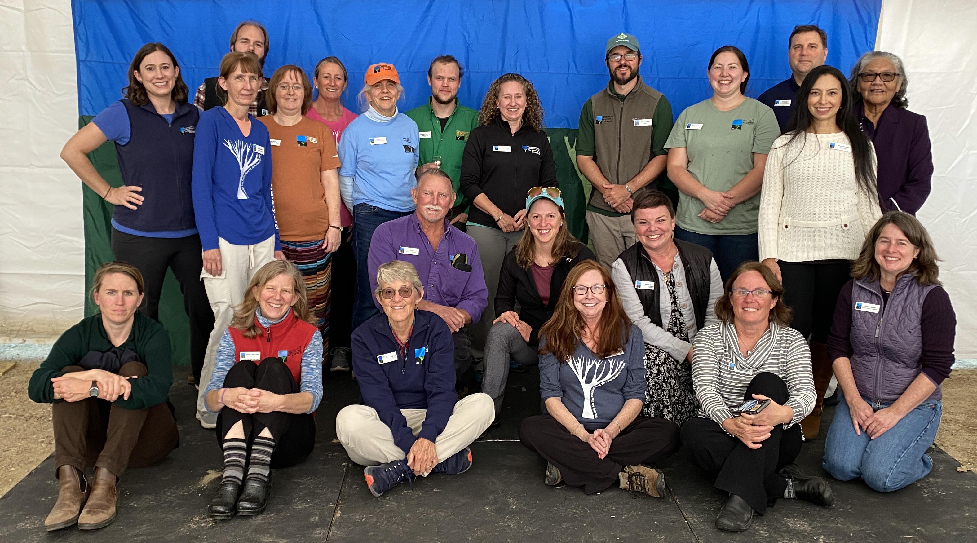 Staff members pose after the Annual Meeting in front of the Forest Society's blue and green flag.