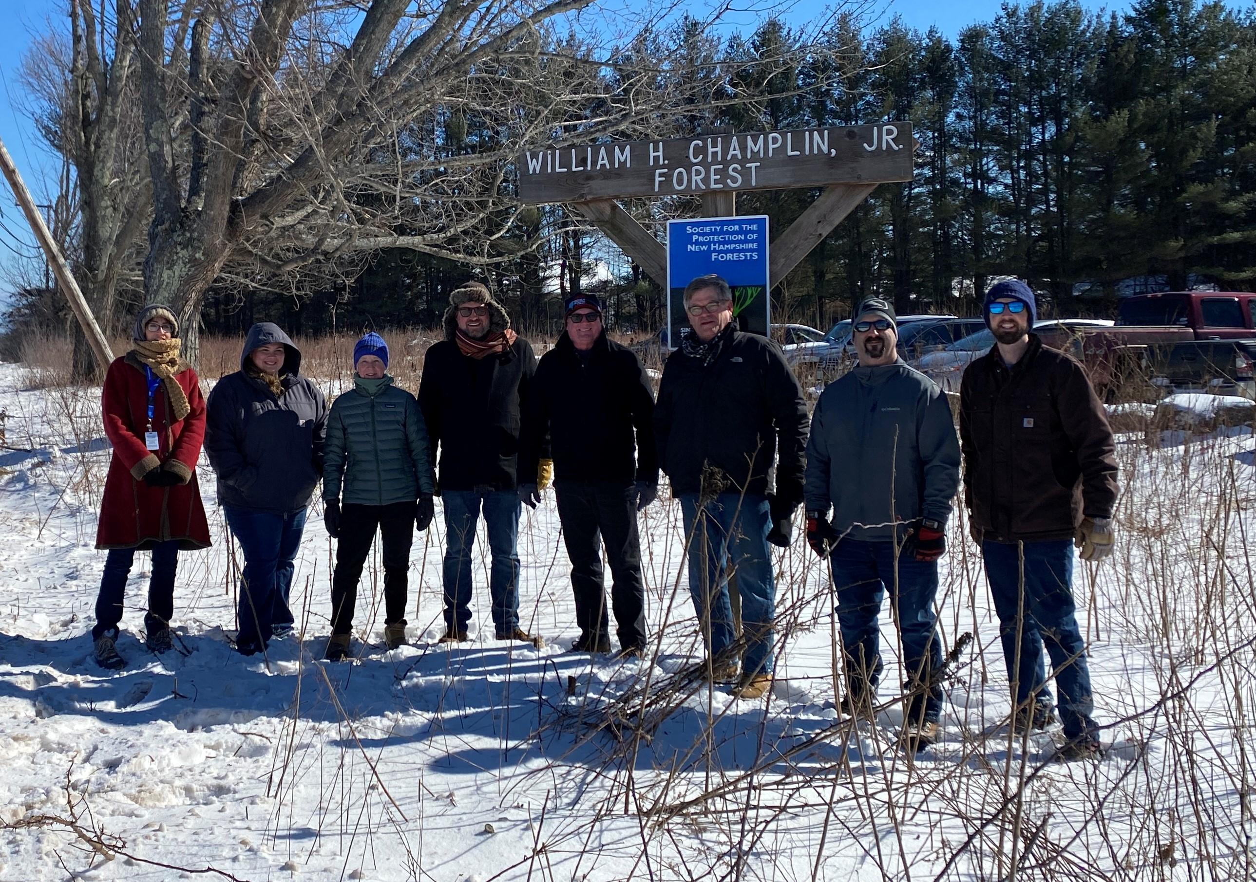 Representatives of the Forest Society and partners on the project stand in front of the official Champlin Forest sign in Rochester.