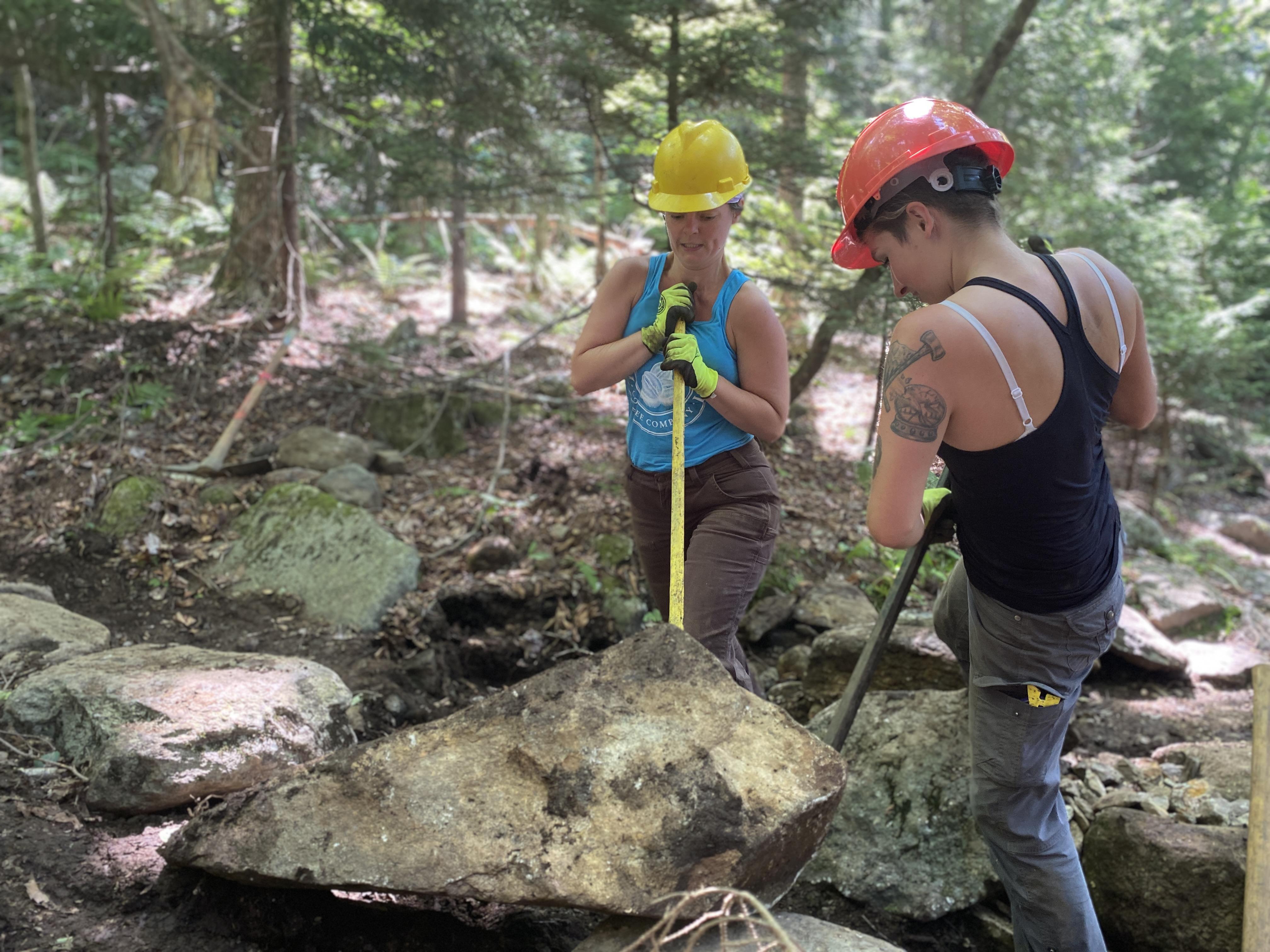 Women lift a rock together.
