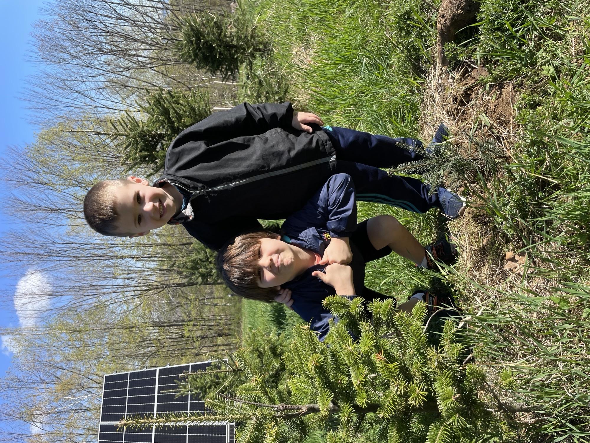 Two children pose with seedlings they planted.