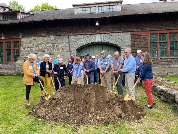 The group poses with golden shovels in front of a pile of dirt.