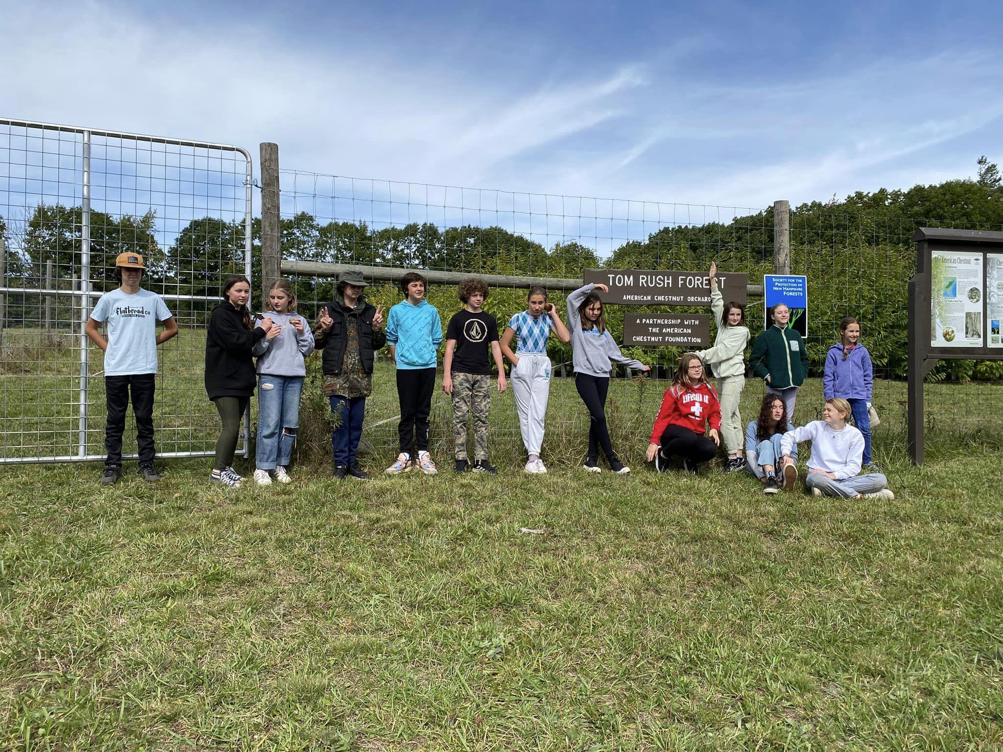 7th graders from The Well School pose in front of the chestnut orchard sign at Tom Rush Forest.