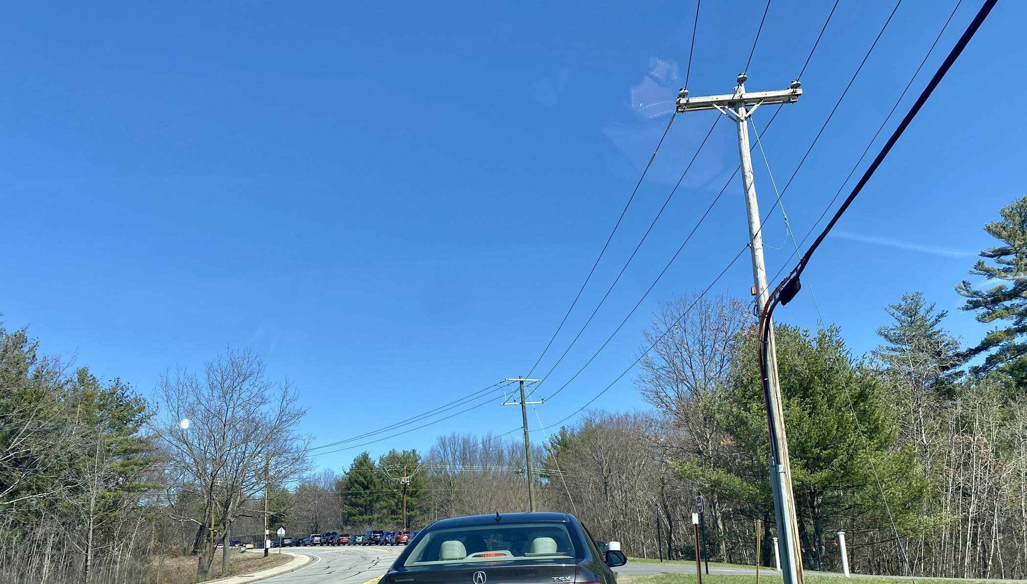 Cars line up on a road with telephone poles near the road.