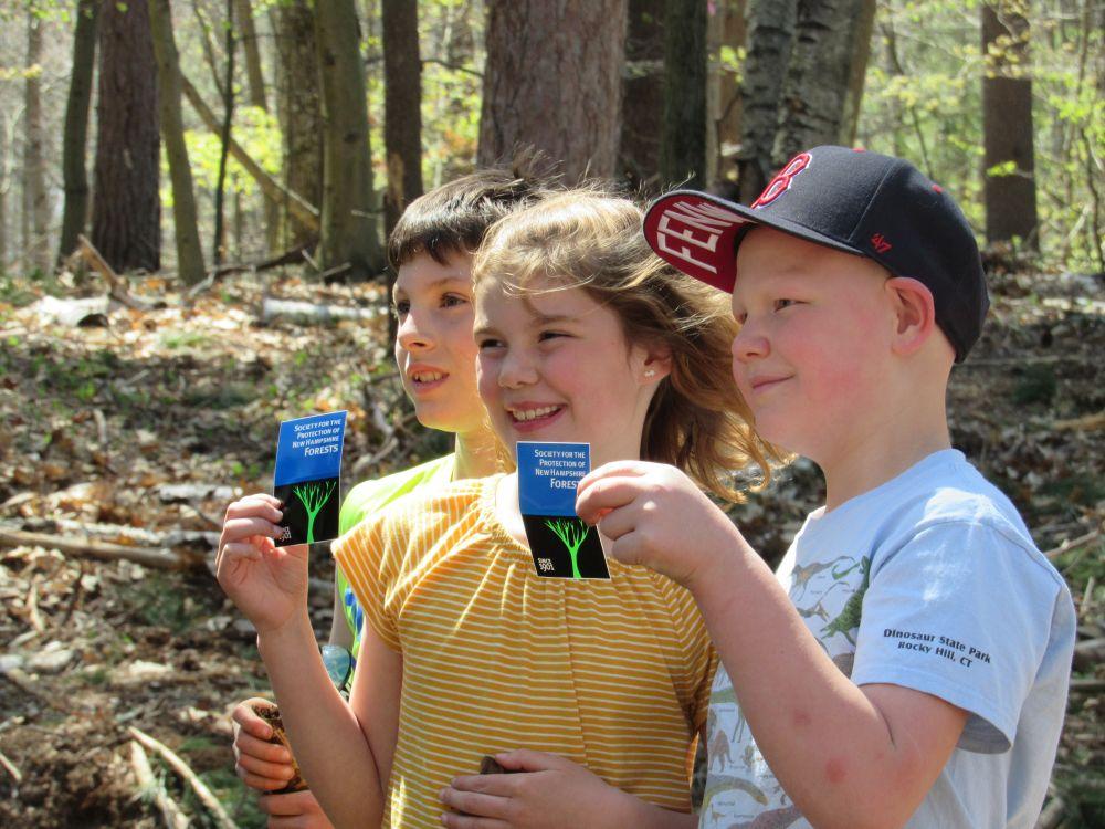 Smiling students hold Forest Society logo stickers
